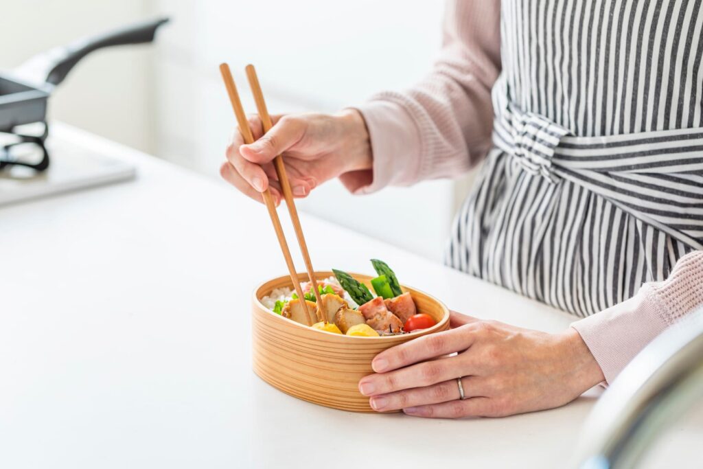 お弁当におかずを詰めている女性