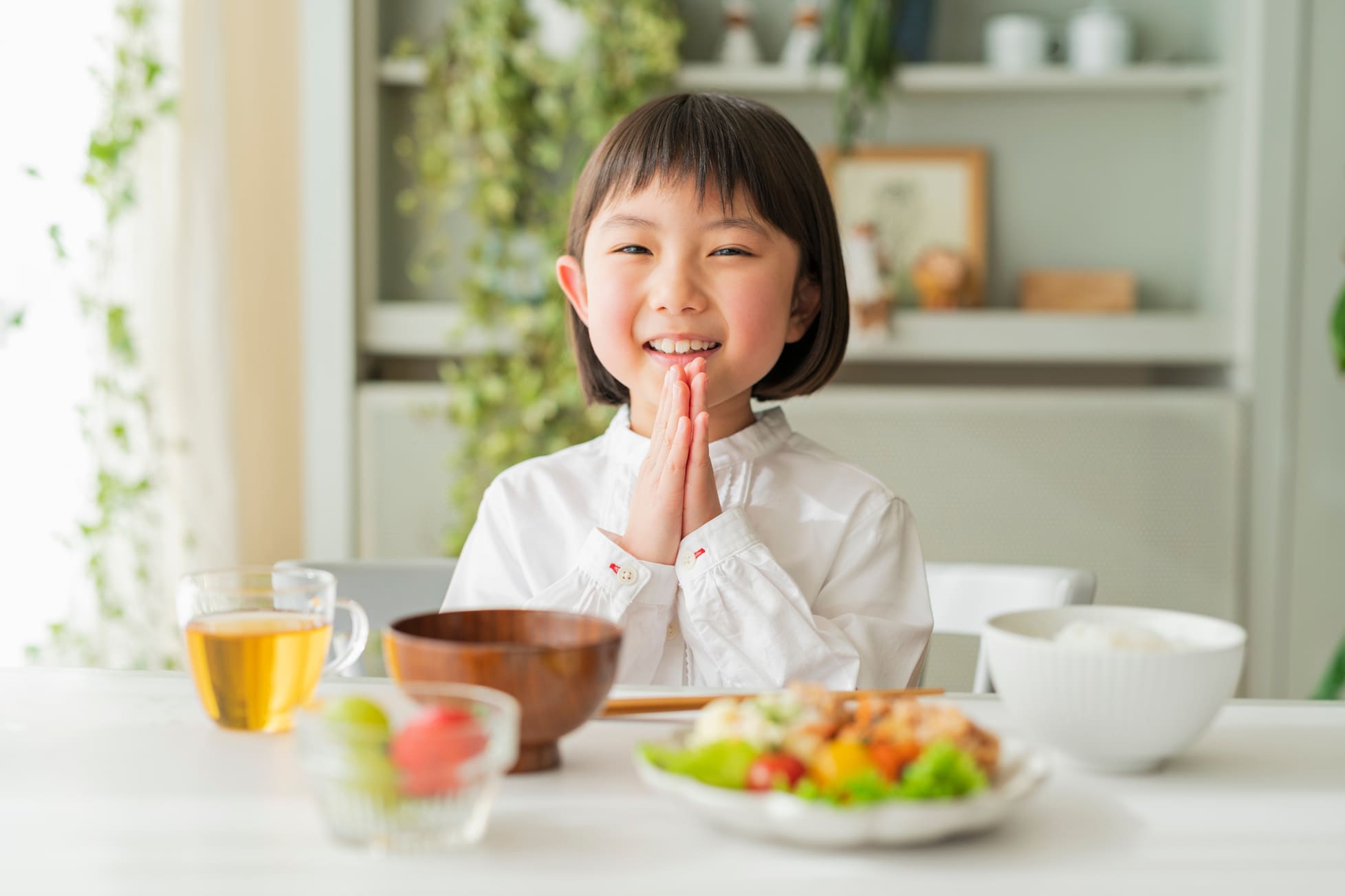 食卓で手を合わせる幼女