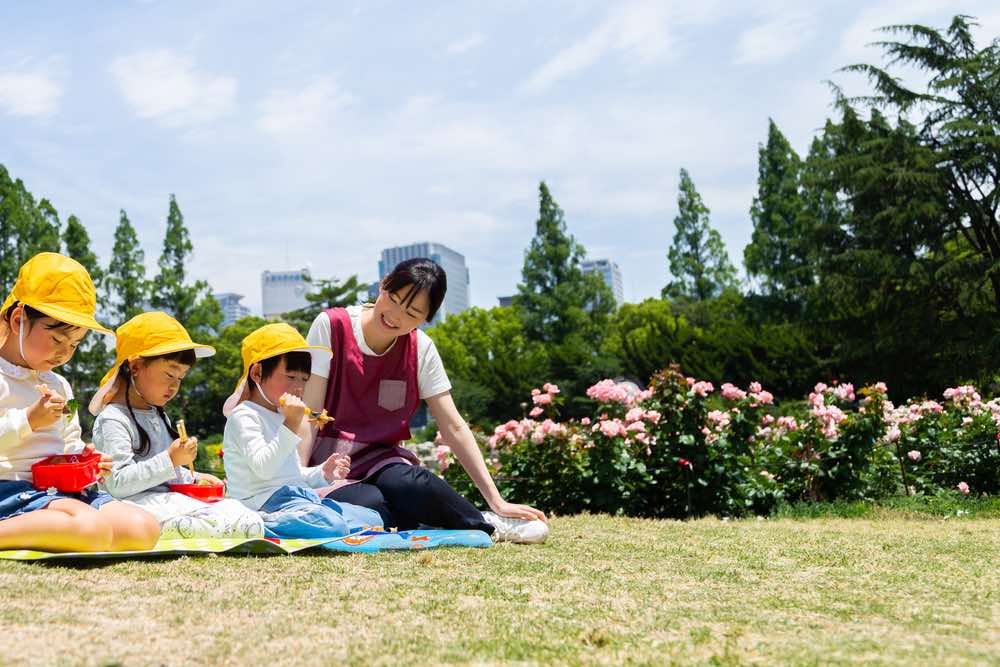 外でお弁当を食べる幼稚園児