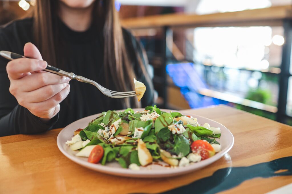 野菜にフォークをいれる女性