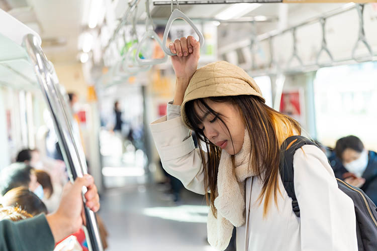 電車でうなだれる女性