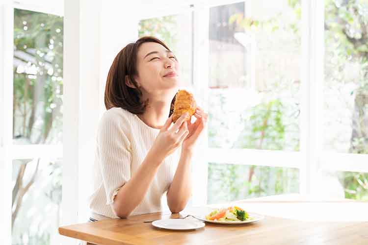 おいしそうに食事をする女性