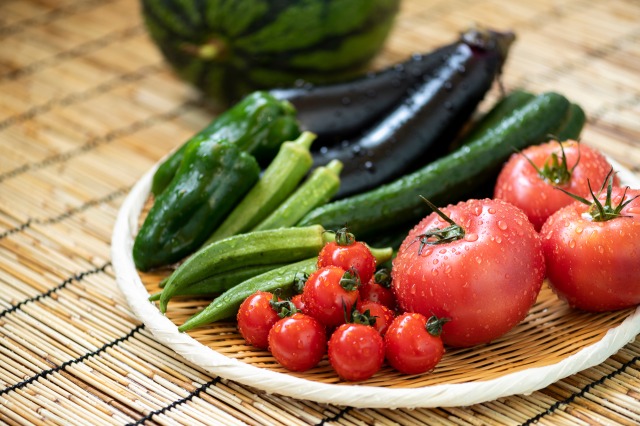 ざるにはいったトマト、ナス、きゅうり、オクラ、ピーマンなどの夏野菜