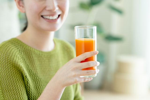 野菜ジュースと、それを持つ女性