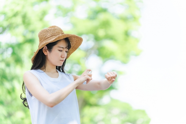 腕にスプレーの日焼け止めをふる女性