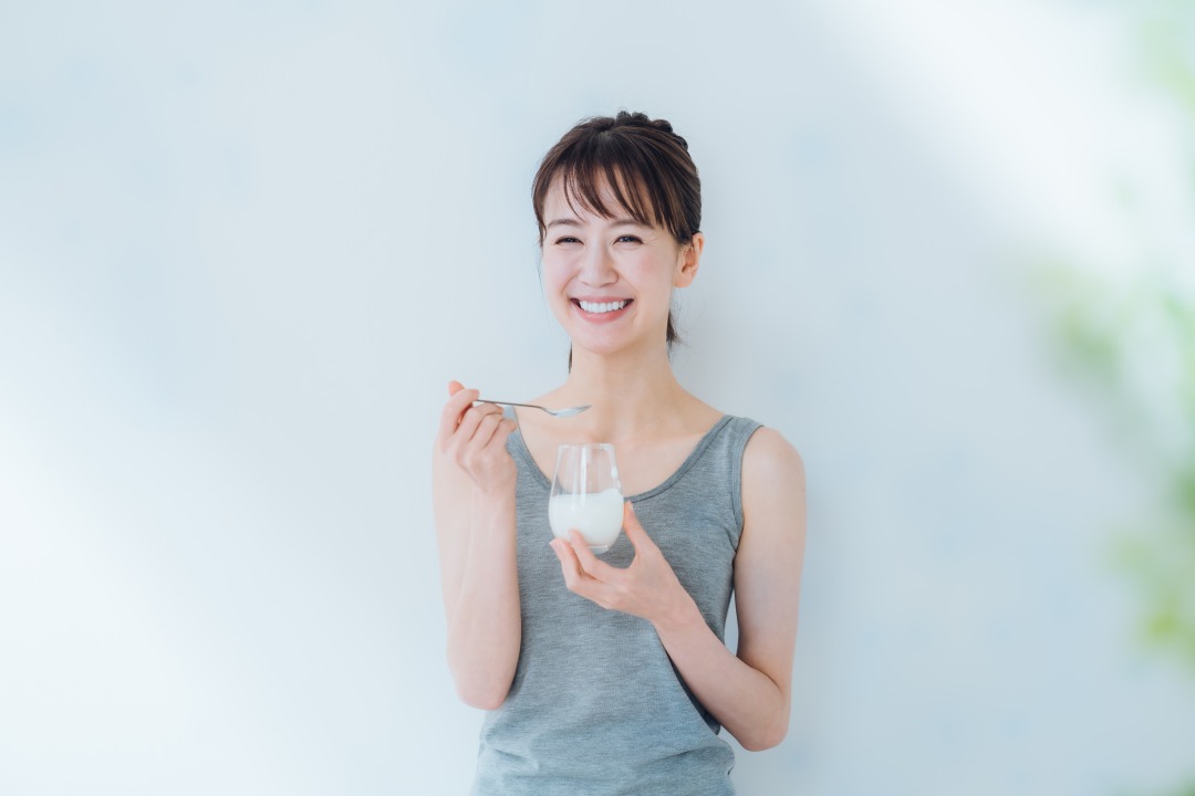 ヨーグルトを食べる笑顔の女性