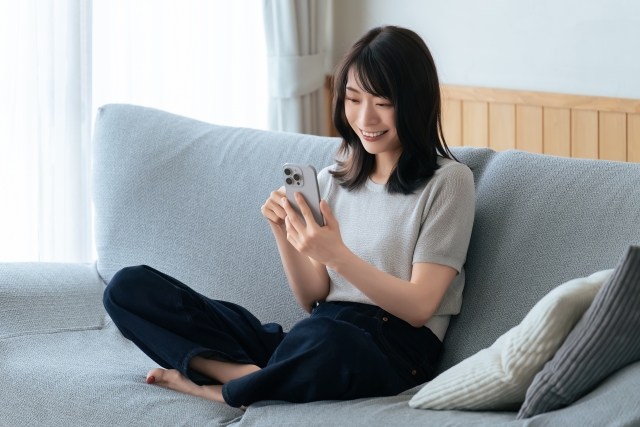 スマホを見る笑顔の女性　調べ物イメージ