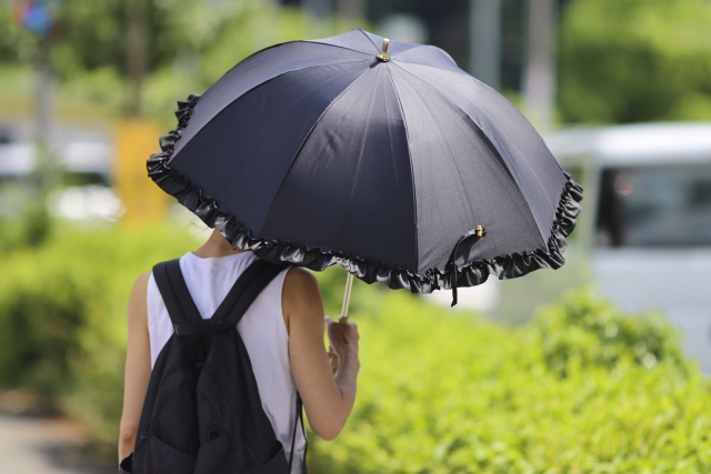 黒い傘をさす女性の後ろ姿　紫外線　熱中症対策