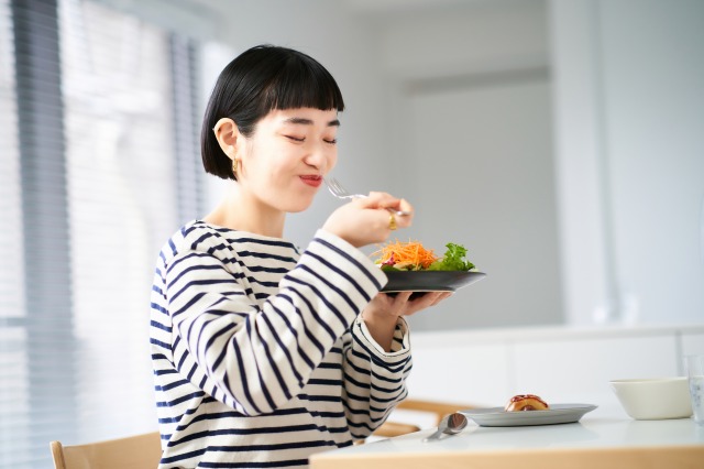 家のダイニングで食事をする女性