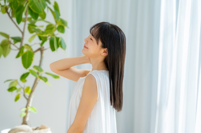 室内　髪をはらう笑顔の女性　ヘアケア