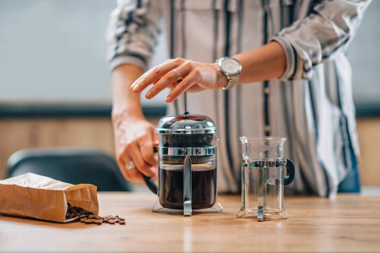 フレンチプレスでコーヒーを淹れる様子　プレス中　女性の手元