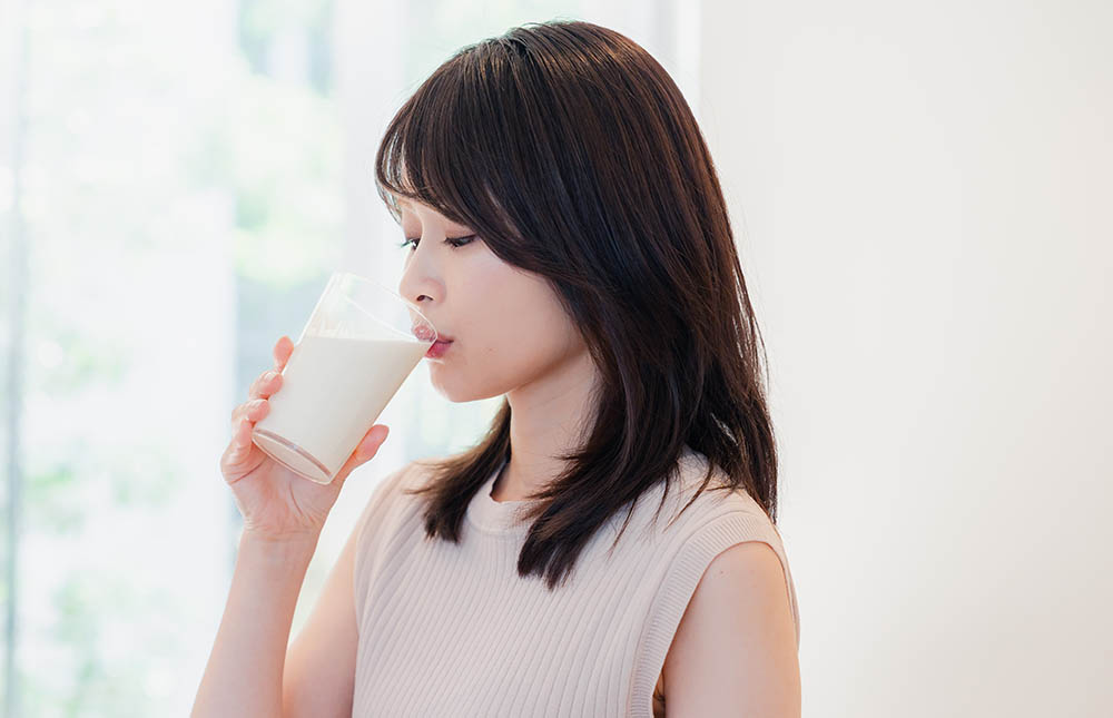家でプロテインを飲む若い女性