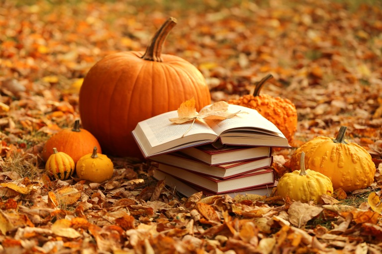 秋の紅葉　落ち葉の中のカボチャと積み上げられた本　10月の読書イメージ