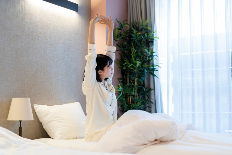 ホテルで朝目覚める女性 快眠 イメージ
