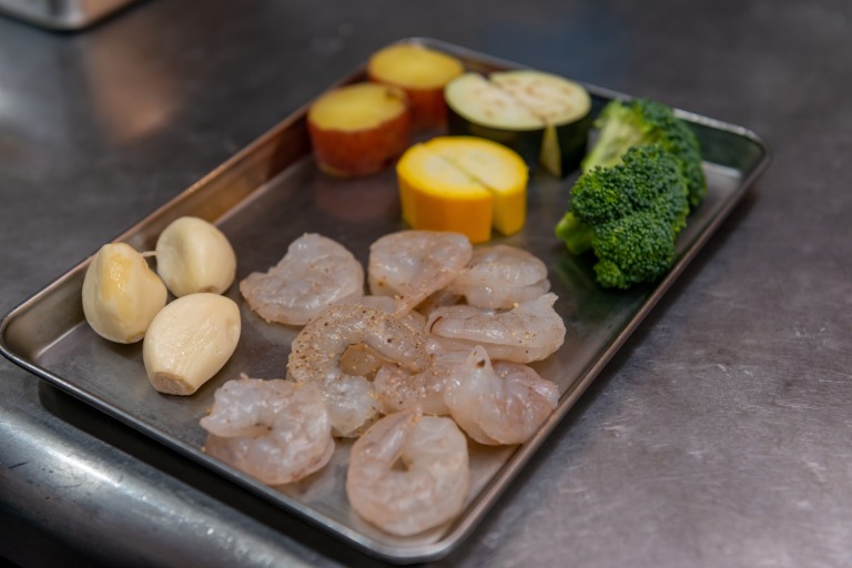 バットの上に並べられた食材(ニンニク えび ブロッコリー ズッキーニ なす さつまいも)