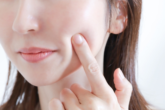 頬を指で押す女性 美肌イメージ