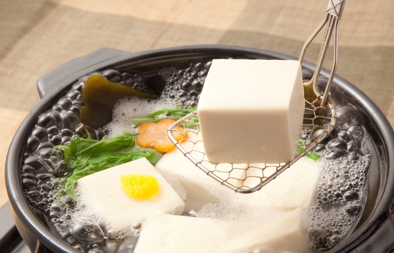 豆腐をすくう様子 昆布と豆腐が入った土鍋 湯豆腐 イメージ