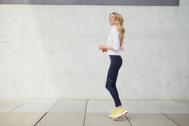 外でジャンプをする女性　運動　エクササイズ