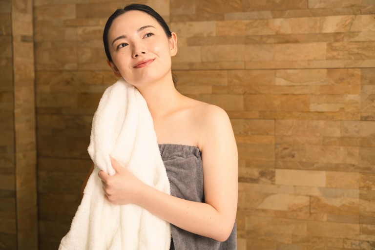 タオルで汗を拭う若い女性 ビューティイメージ