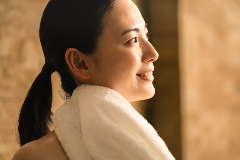 タオルで汗を拭う若い女性　ビューティイメージ 