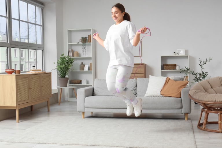 笑顔の女性が部屋でなわとびをする様子　運動 エクササイズ　イメージ