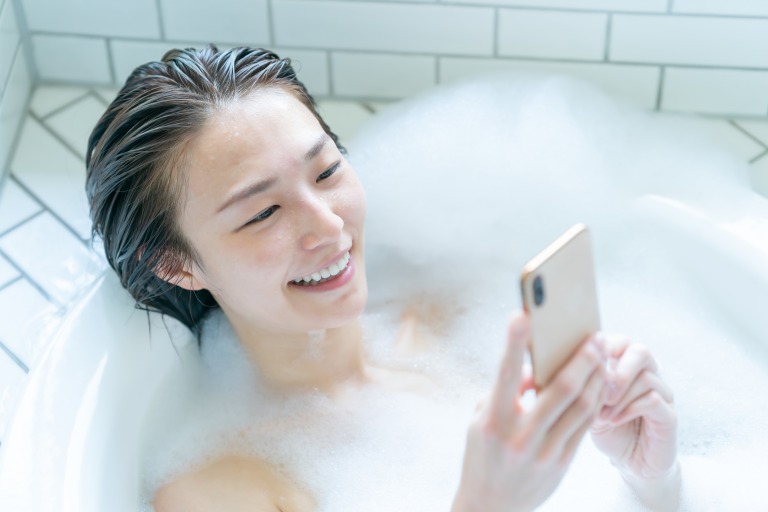 お風呂でスマートフォンをいじる女性