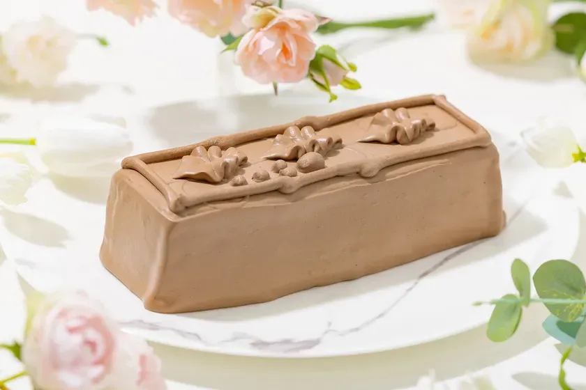 チョコレートケーキが皿に載せられ、周りに花が飾られている写真です。