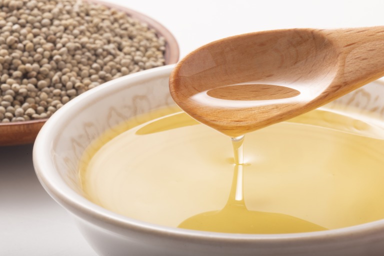 えごまの実を背景に木製スプーンでえごま油をすくう様子