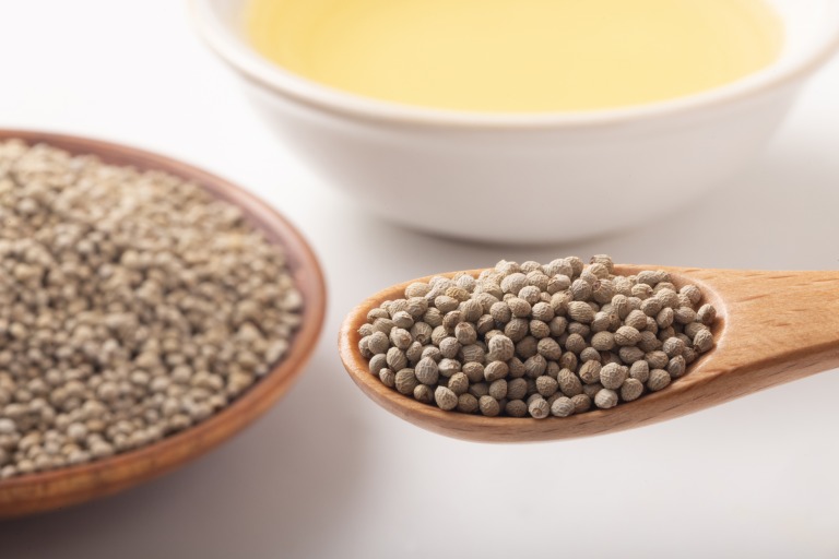 エゴマの実とえごま油を背景に、実を木製スプーンですくう様子