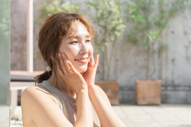 両手で顔の肌に触れる女性
