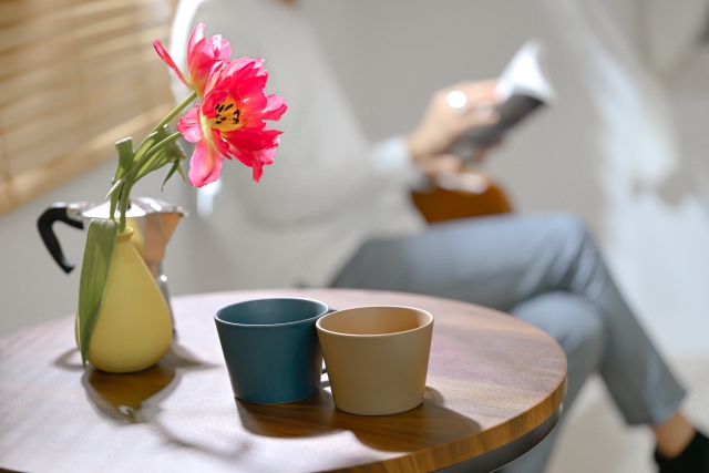 自宅で日向ぼっこをしながら読書をする人 お花と陶器インテリア