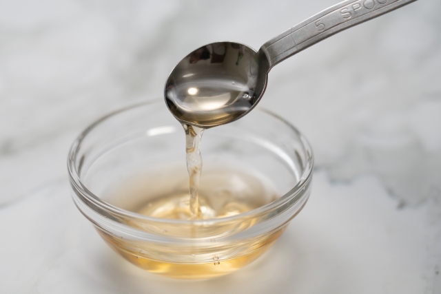 調味料 ガラス小皿に入ったお酢をスプーンですくう様子