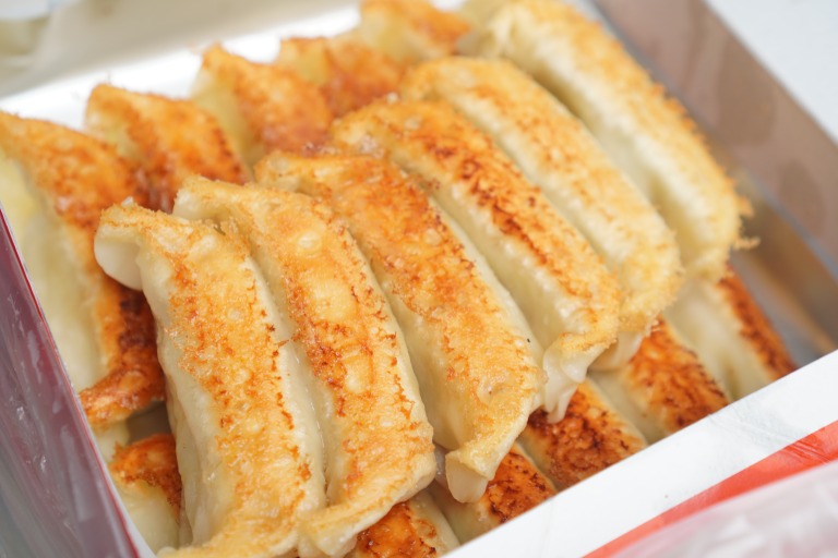 香ばしく焼き上がった宇都宮餃子のアップ写真　黄金色の焼き目が美味しそうに並ぶテイクアウト餃子　中華料理の定番メニューで家庭料理や外食、食欲をそそる食文化を表現したフードイメージ 