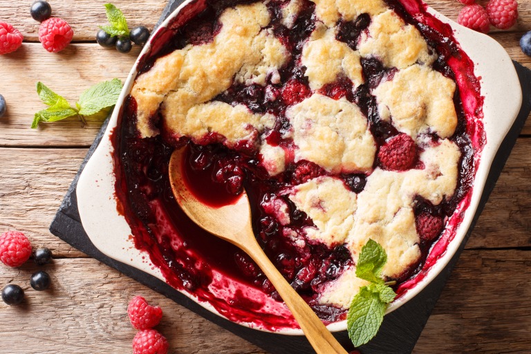Berry cobbler with currants, raspberries and blueberries decorated with mint close up. Horizontal top view スグリ、ラズベリー、ブルーベリーを使いミントで飾ったベリーコブラーのクローズアップ。横位置・真上からの視点