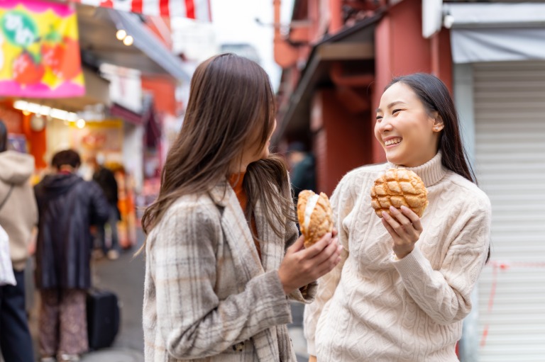 浅草で食べ歩きする女性たち　メロンパンを手にして談笑