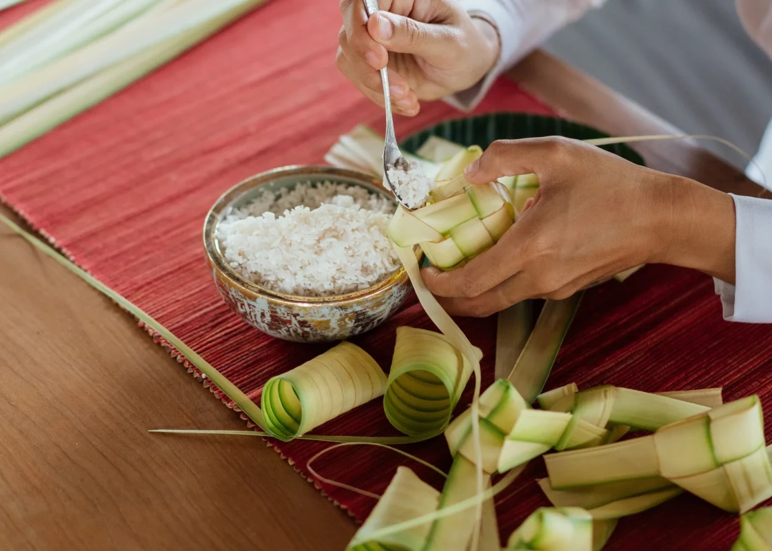 ココナッツの葉で包まれた米料理、ケトゥパットを調理している様子。