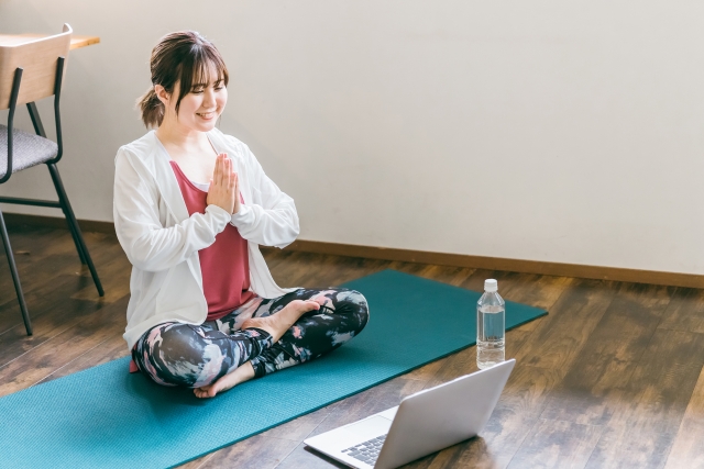 パソコンを見ながらヨガする女性　オンライン教室イメージ