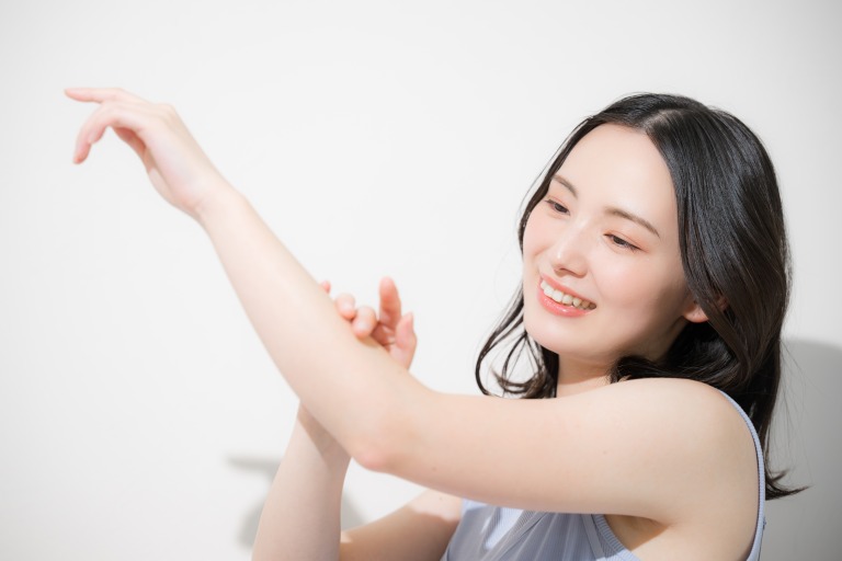 日焼け止めを塗るかわいい女性　腕に日焼け止めなどを塗る　夏の日差しと暑さ対策