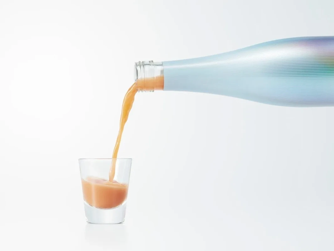 ボトルからグラスに液体が注がれている様子を写した写真。背景は白で、シンプルでクリーンな印象を与える。