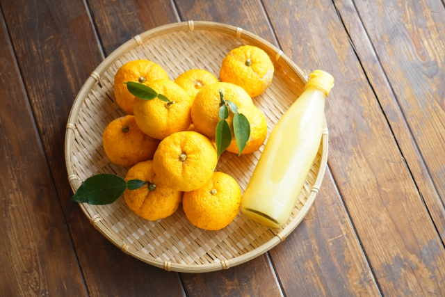 ざるに乗ったゆず複数こと、ゆず果汁の入った瓶