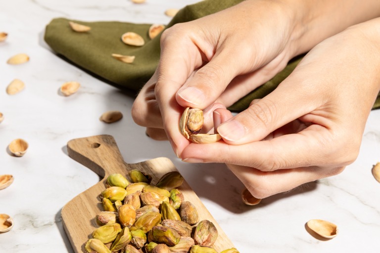 机の上のピスタチオの殻をむいている手