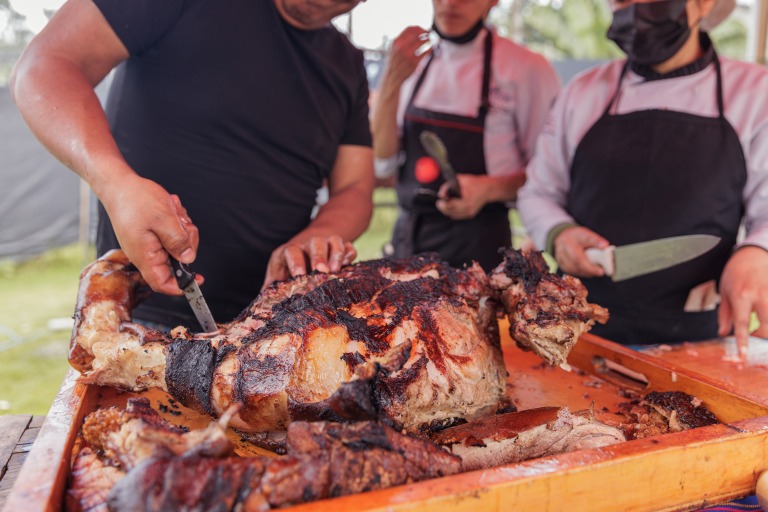 伝統的な屋外バーベキューで、炭火の余熱を使い丸ごとの豚をじっくり焼いている