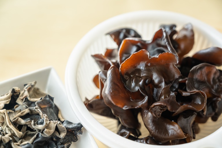 水で戻したキクラゲがザルに入っている　背景に乾燥きくらげ