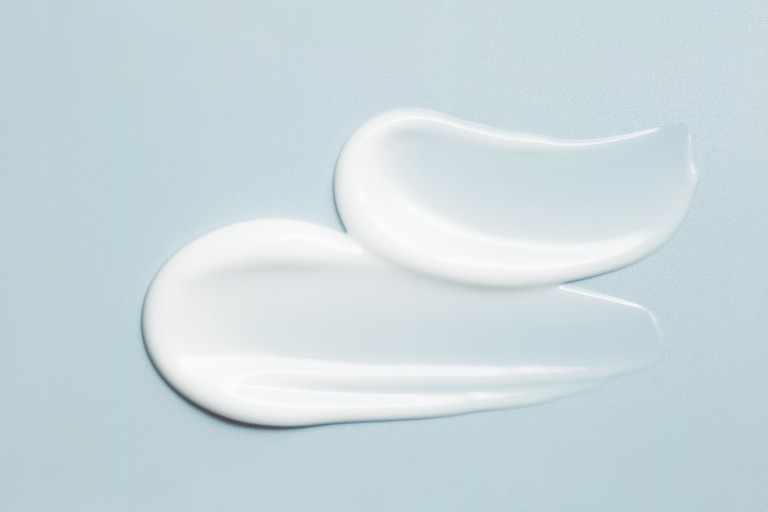 スキンケアクリーム、フェイスセラム、ローションをシルバーブルーの背景に塗りつけたサンプル。白くクリーミーな化粧品を塗りつけたクローズアップ 日焼け止めイメージ