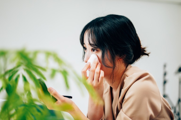 笑顔でメイクをする若い女性 メイク直し