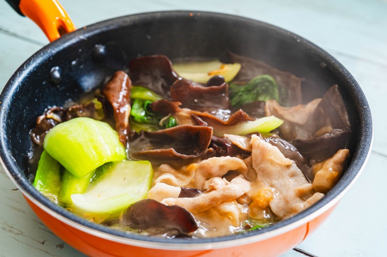 フライパンで青梗菜やきくらげの入った炒め物を加熱する様子