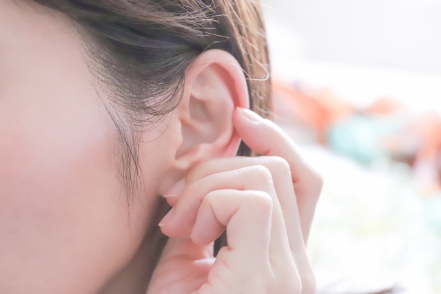 指で耳をつまむ女性の耳元