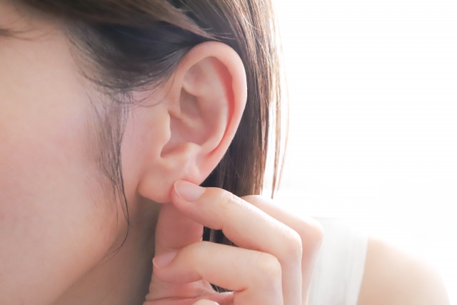 指で耳たぶをつまむ女性の耳元