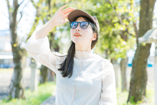 紫外線対策　サングラスと帽子をして外に出る女性
