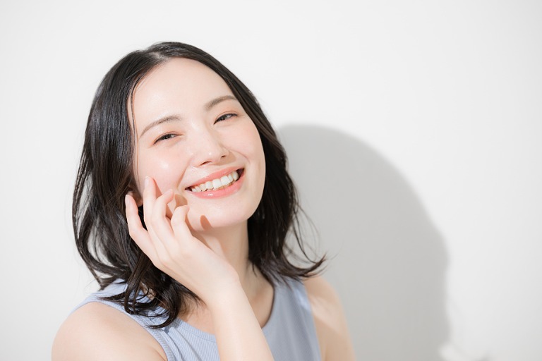 スキンケア　頬に手を添える笑顔の女性　美容イメージ美容イメージ